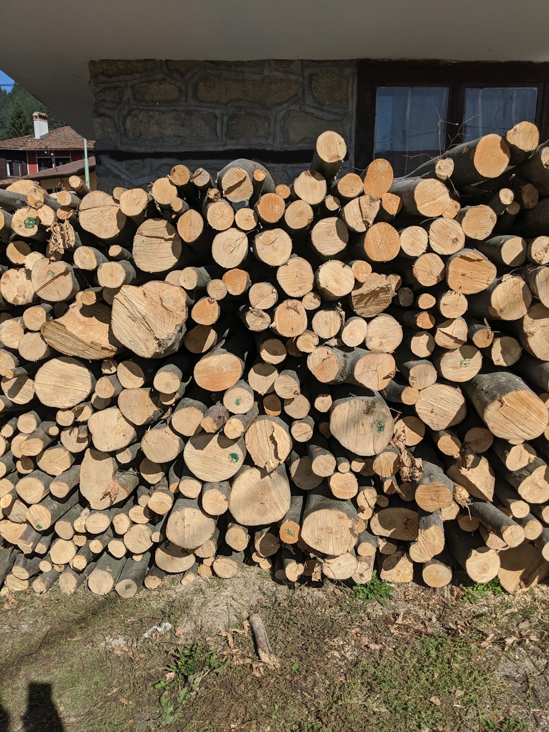 Bûches de bois de chauffage soigneusement empilées contre un mur en pierre et en stuc.